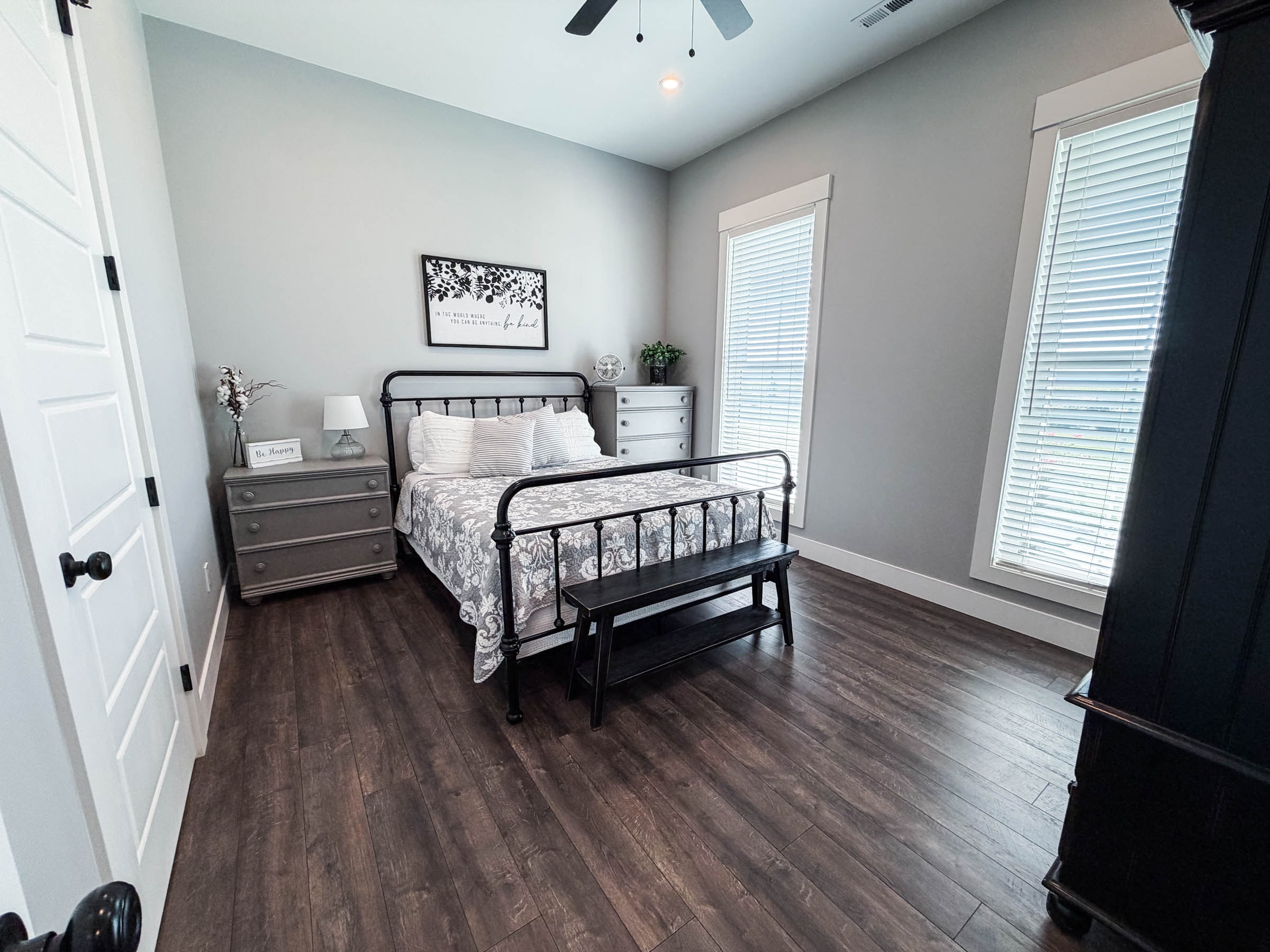 Bedroom 2 with iron bed frame, dark hardwood floors, and ceiling fan