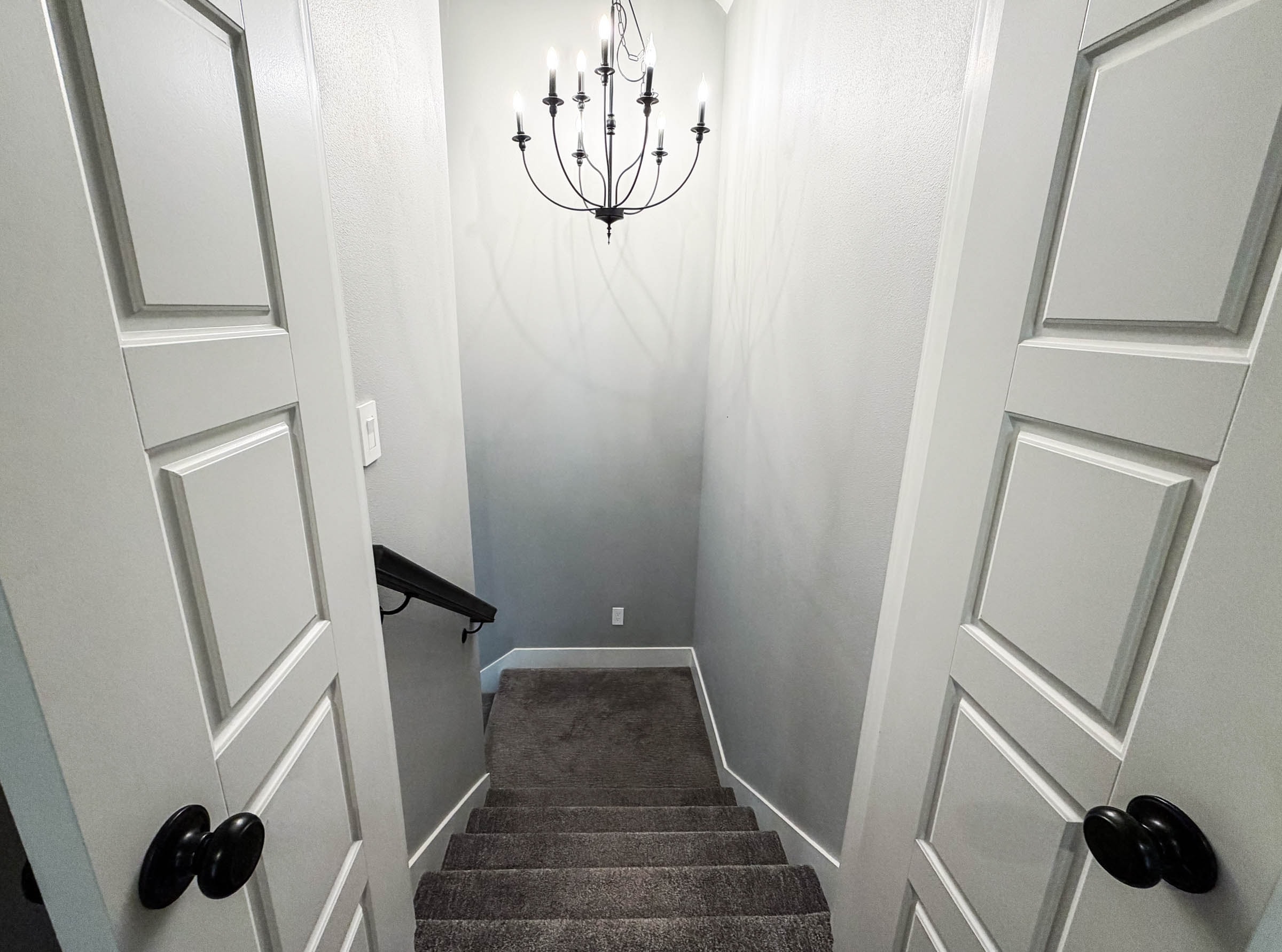 Bonus room staircase with chandelier and white paneled doors