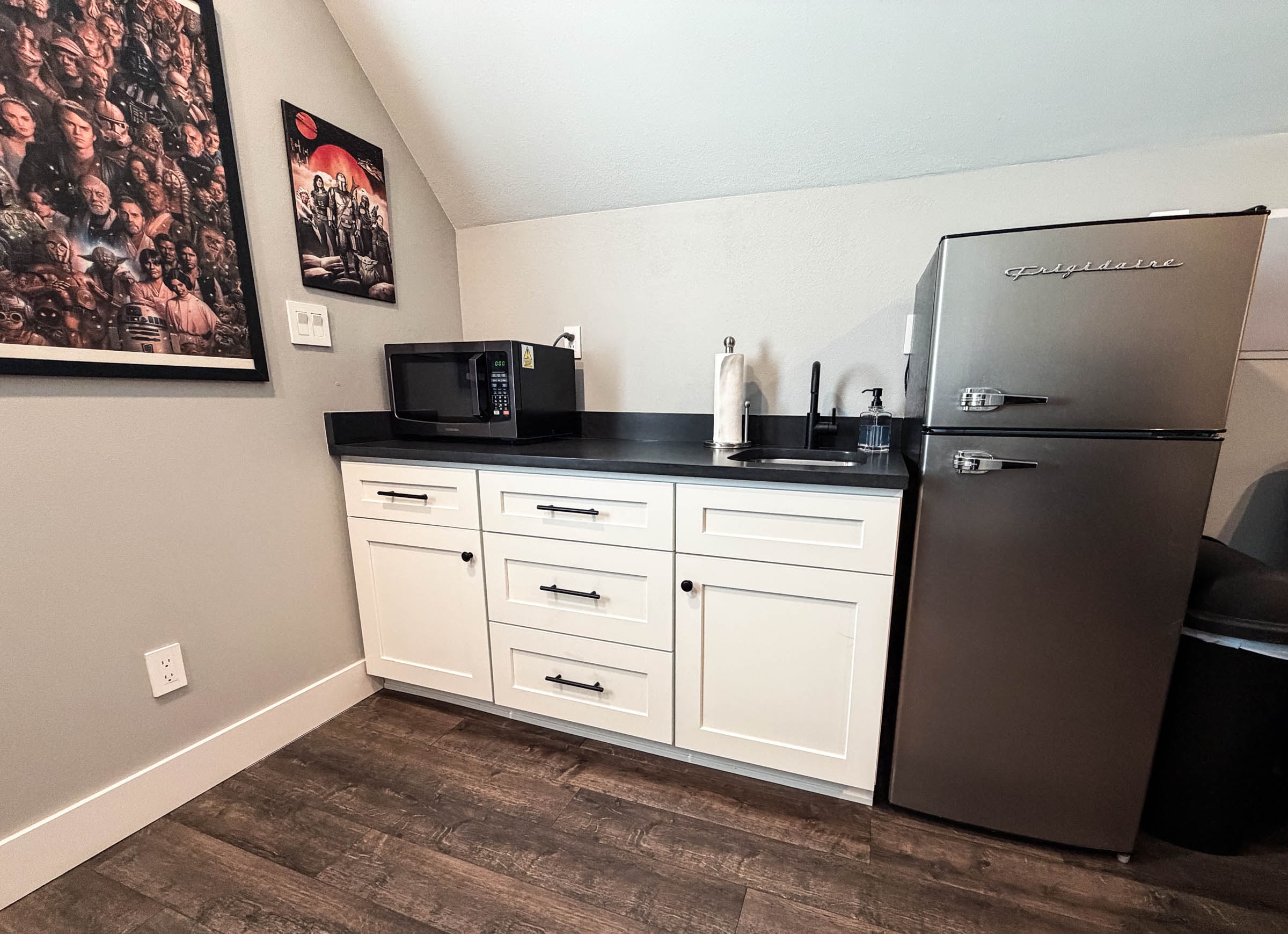Bonus room wet bar with white cabinets, black countertop, and mini fridge