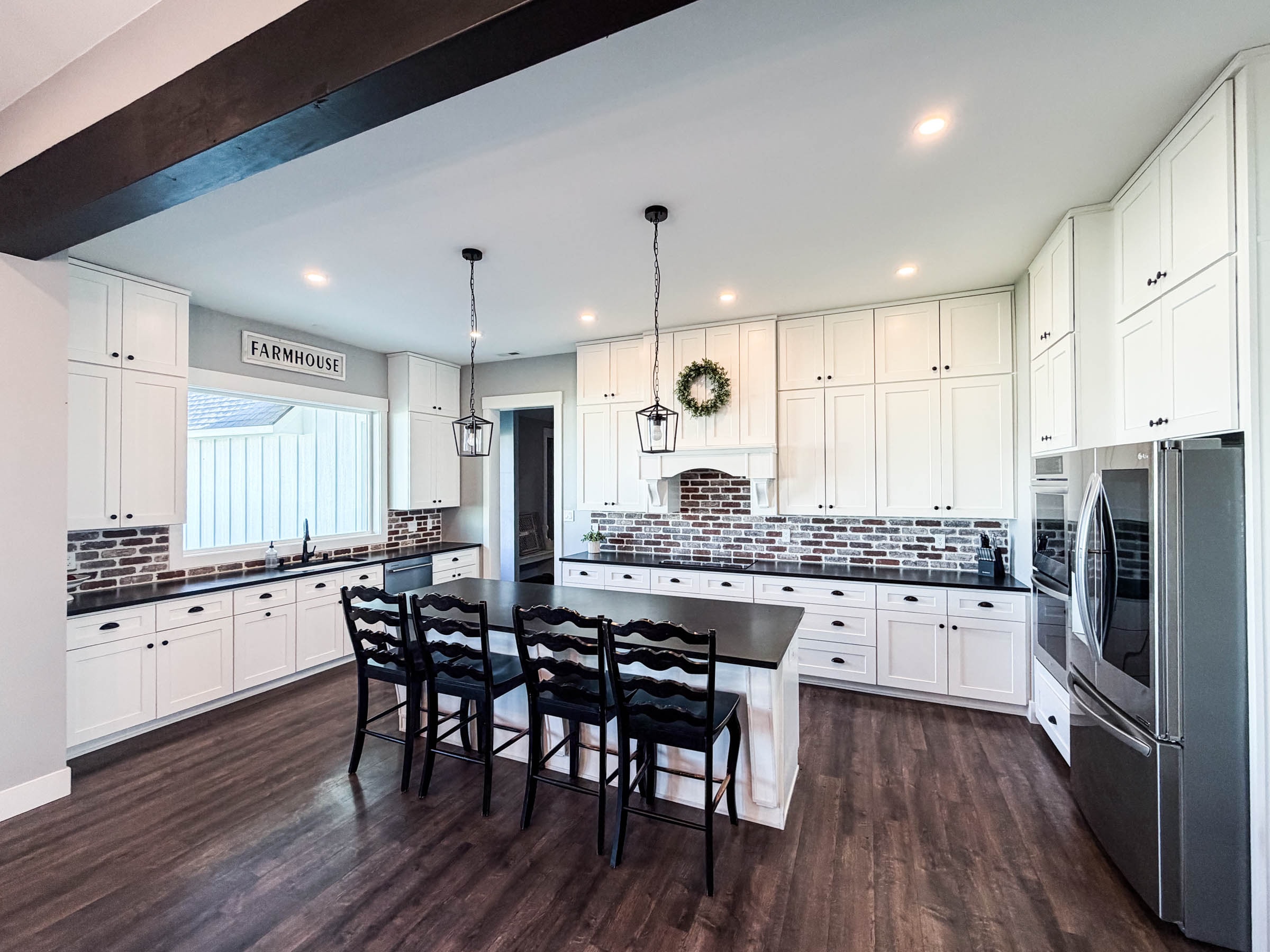 Kitchen counter with white cabinets, black countertops, and brick backsplash