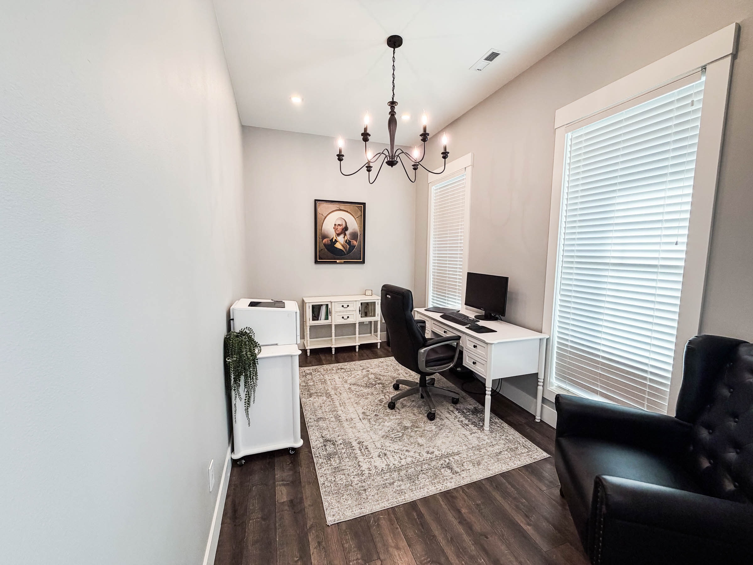 Office with chandelier, white desk, and large window
